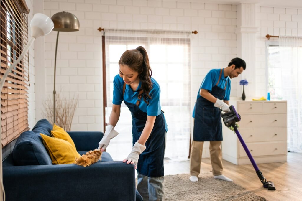 Asian young man and woman cleaning service worker work in living room.